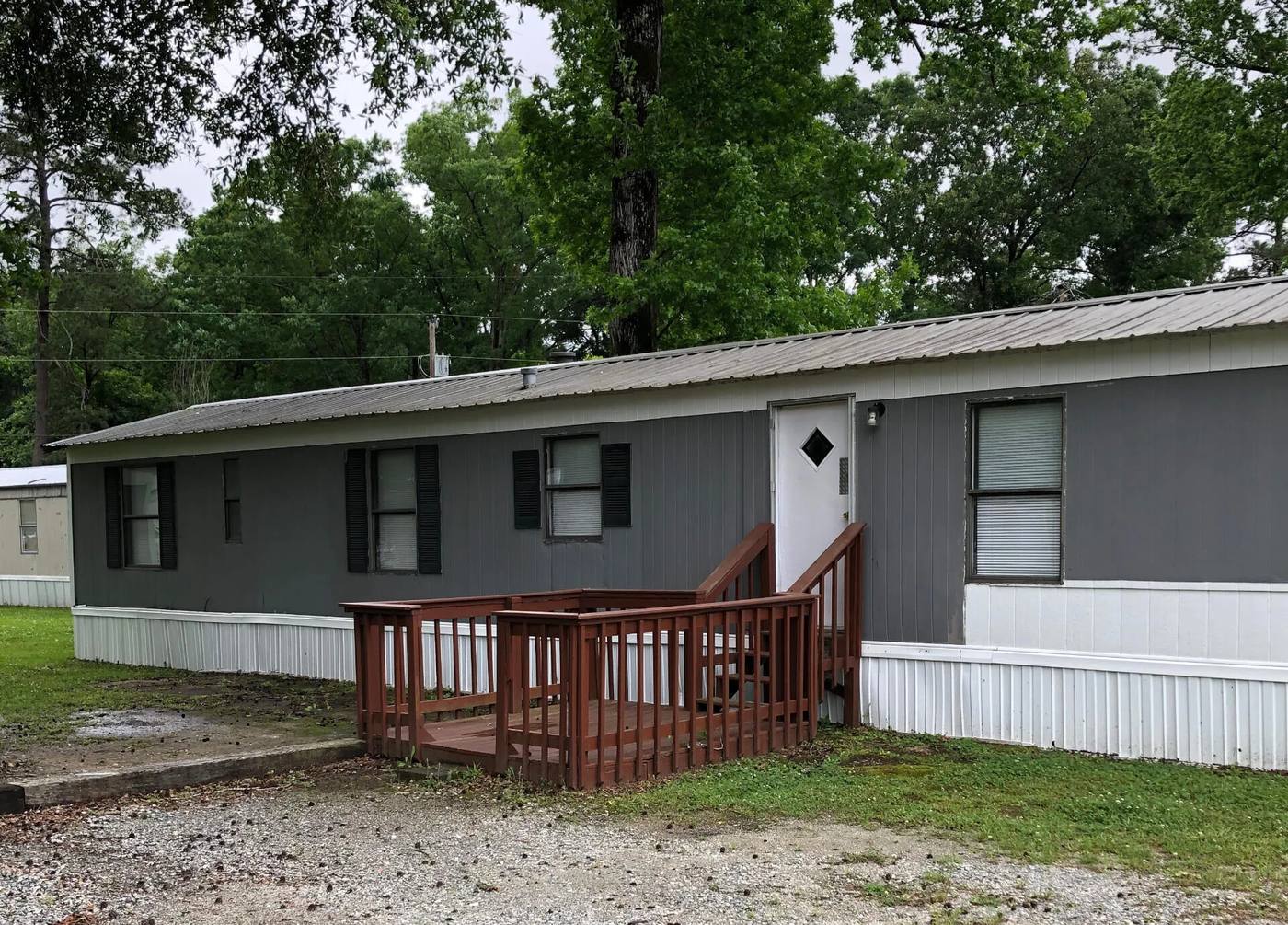 Gray rental home with a wooden porch and shade tree