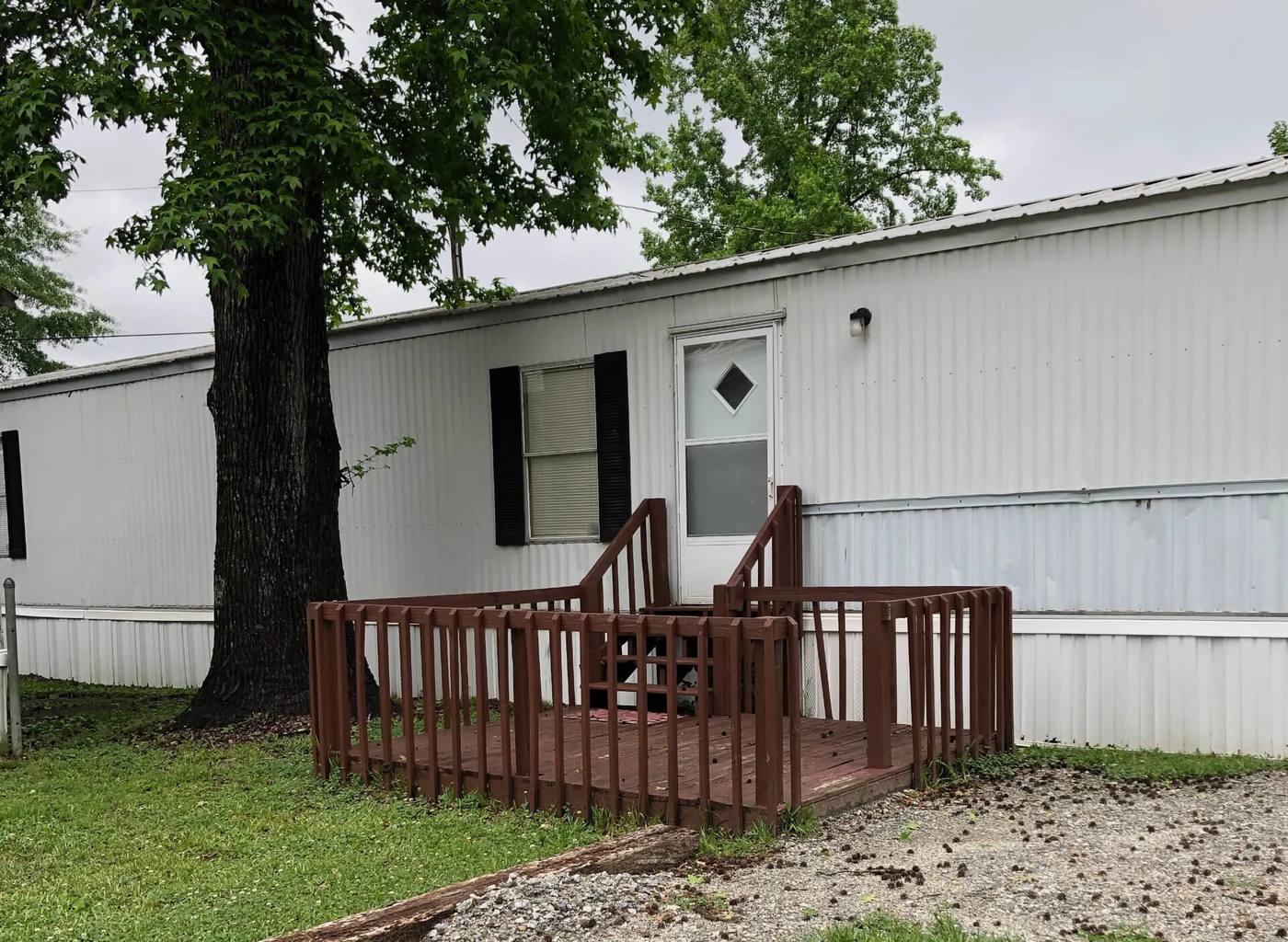 White rental home with a porch under a large tree